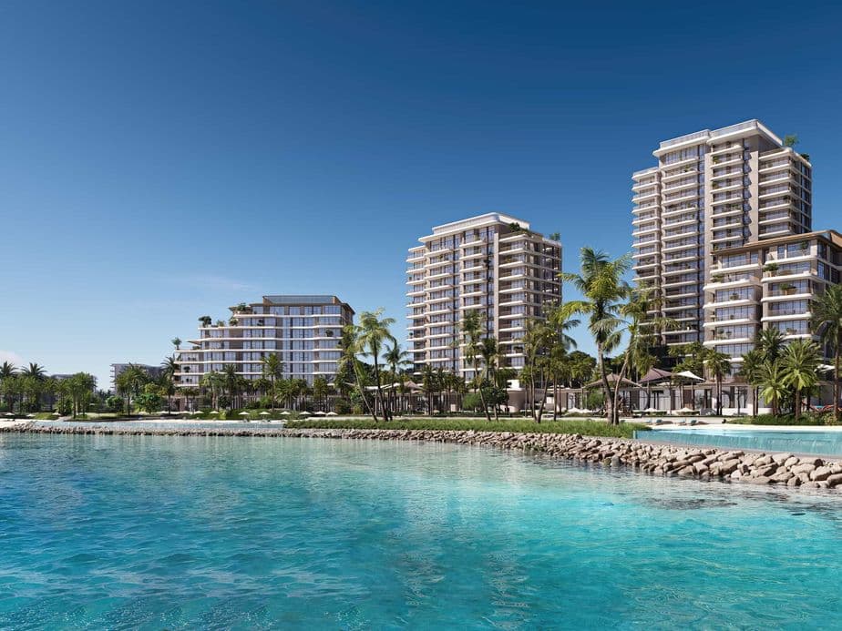 Luxuriöse Strandwohnungen mit Balkonen bieten einen Blick auf türkisfarbenes Wasser und Palmen unter einem klaren blauen Himmel.