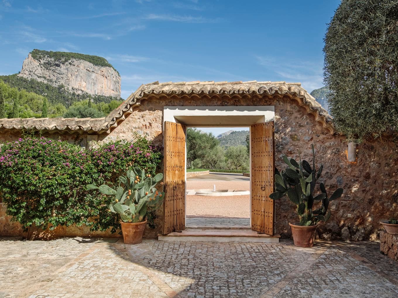 Vista aèria de la finca Turmalina a Alaró, Mallorca, envoltada de vegetació exuberant, oliveres i els dramàtics cims bessons de la Serra de Tramuntana.