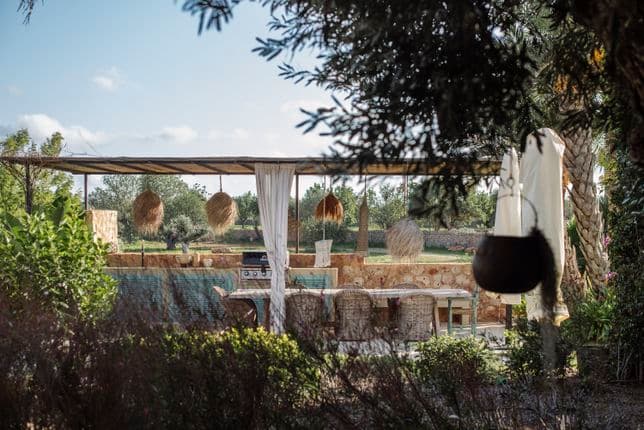 Amplia terraza exterior con suelo de piedra natural, cómodos asientos de salón y vistas despejadas del paisaje mediterráneo circundante, ofreciendo un espacio exterior de vida sereno y lujoso.