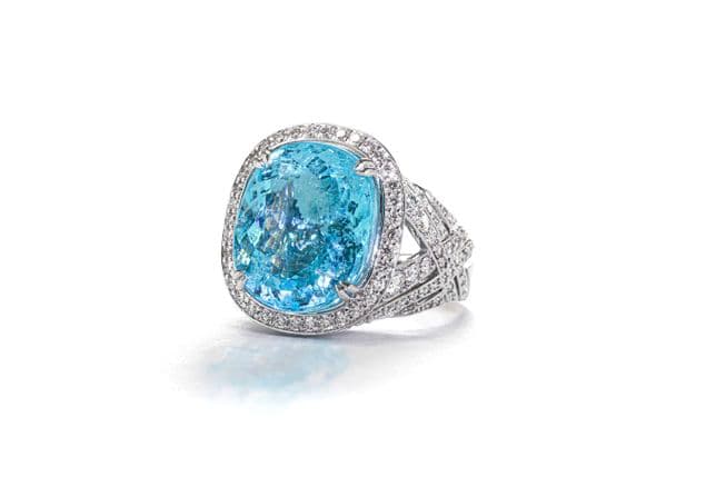 A silver ring with a large, oval, light blue gemstone surrounded by small diamonds.