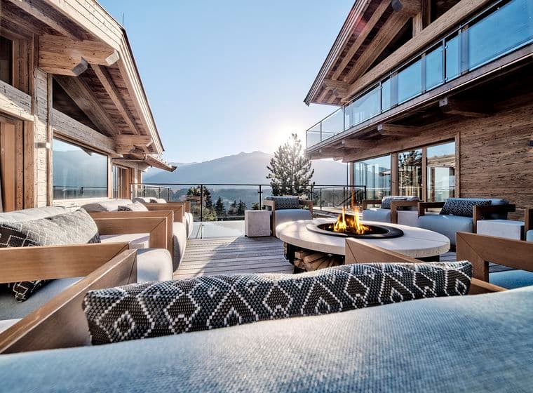 Chalet-Terrasse mit gemütlichen Sitzmöglichkeiten, Feuerstelle und Bergblick.