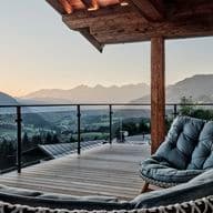 Terrace of a chalet with armchairs and panoramic views of the Alps.