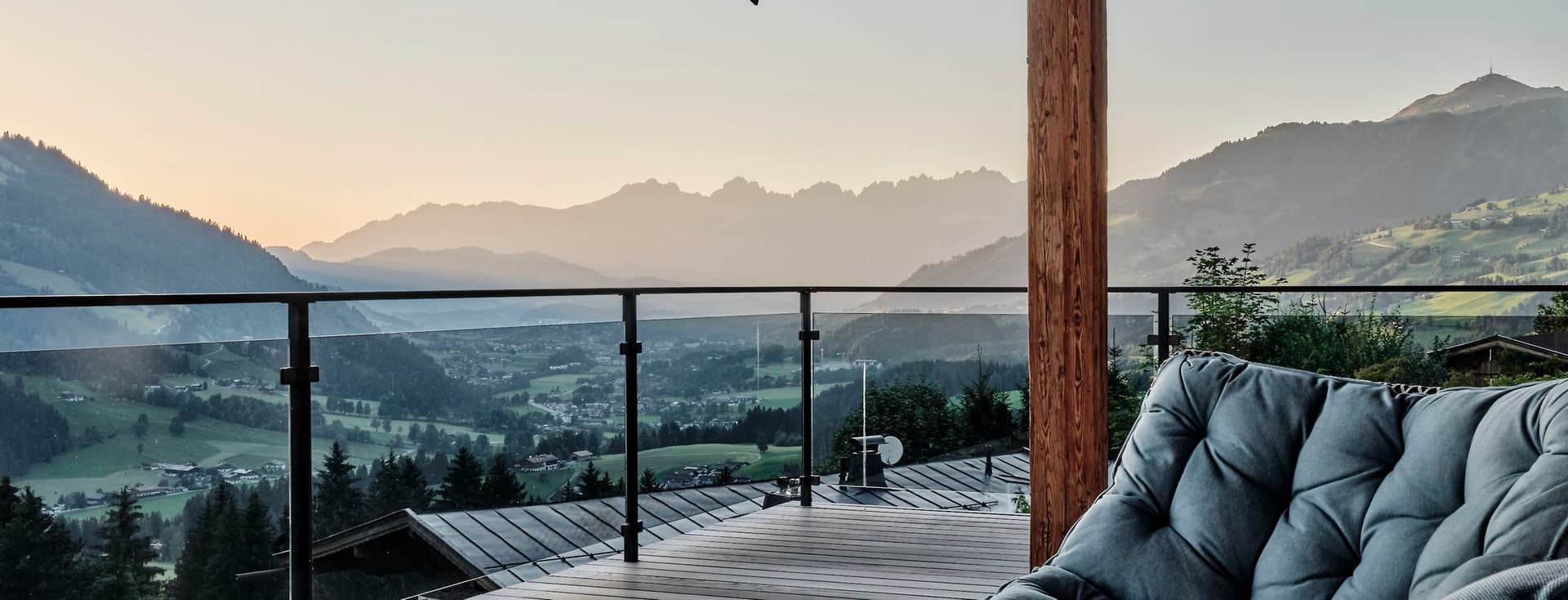 Terrasse eines Chalets mit Sesseln und Panoramablick auf die Alpen.