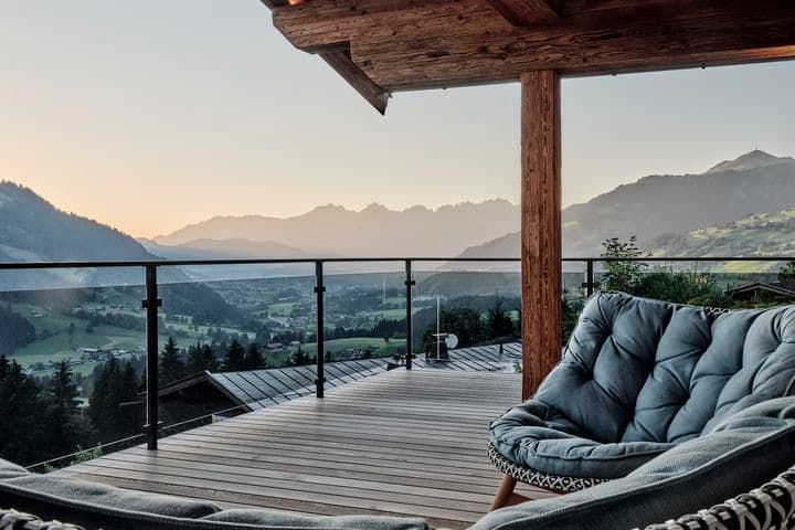 Terrasse eines Chalets mit Sesseln und Panoramablick auf die Alpen.