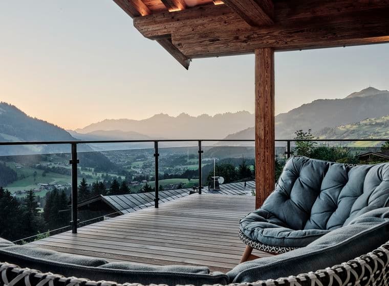 Terrasse eines Chalets mit Sesseln und Panoramablick auf die Alpen.