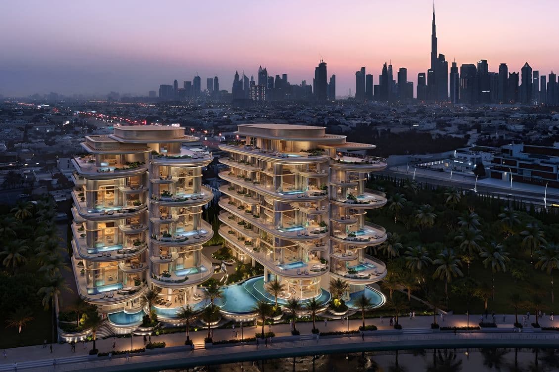 Luxurious, illuminated buildings with pools, set against a city skyline at dusk, featuring a prominent tall tower in the background.