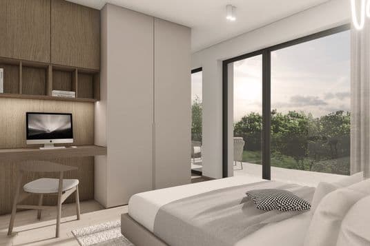 Bedroom with a built-in wooden workspace, a computer on the desk, a large window, and a view of the terrace with greenery.