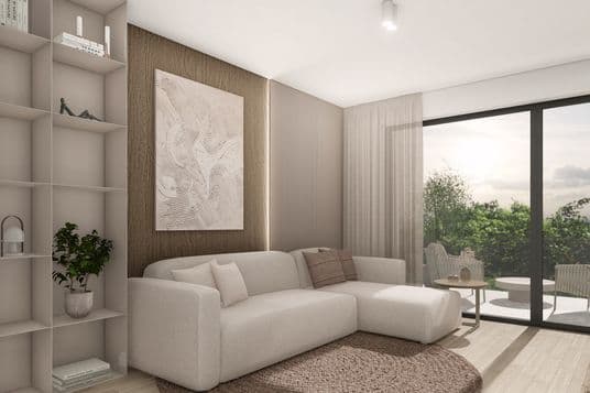 Modern living room with a large light-colored sofa, wooden wall panel, shelving unit, round rug, and a view through a large window onto a terrace with greenery.
