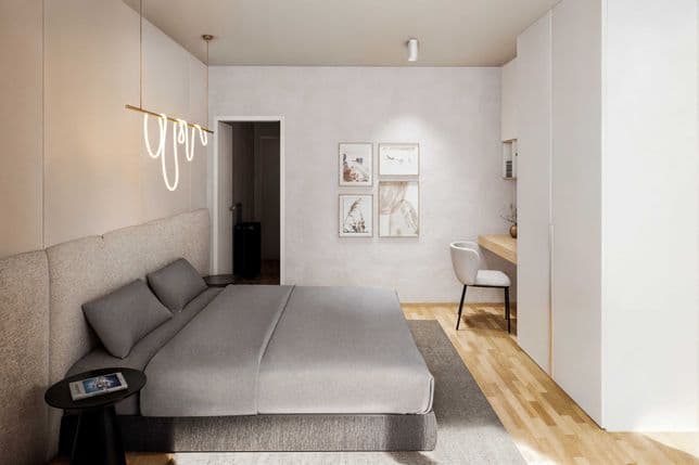 Modern bedroom with a gray upholstered bed, pendant lighting, writing desk, and four framed pictures on the wall, featuring light colors and a wooden floor.