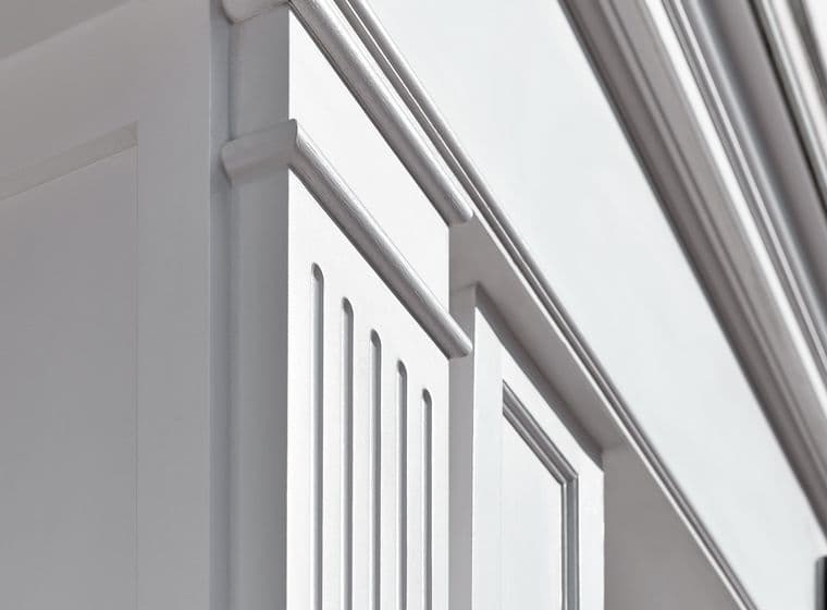 Close-up view of an elegant white building facade featuring decorative window frames and horizontal moldings in a traditional architectural style