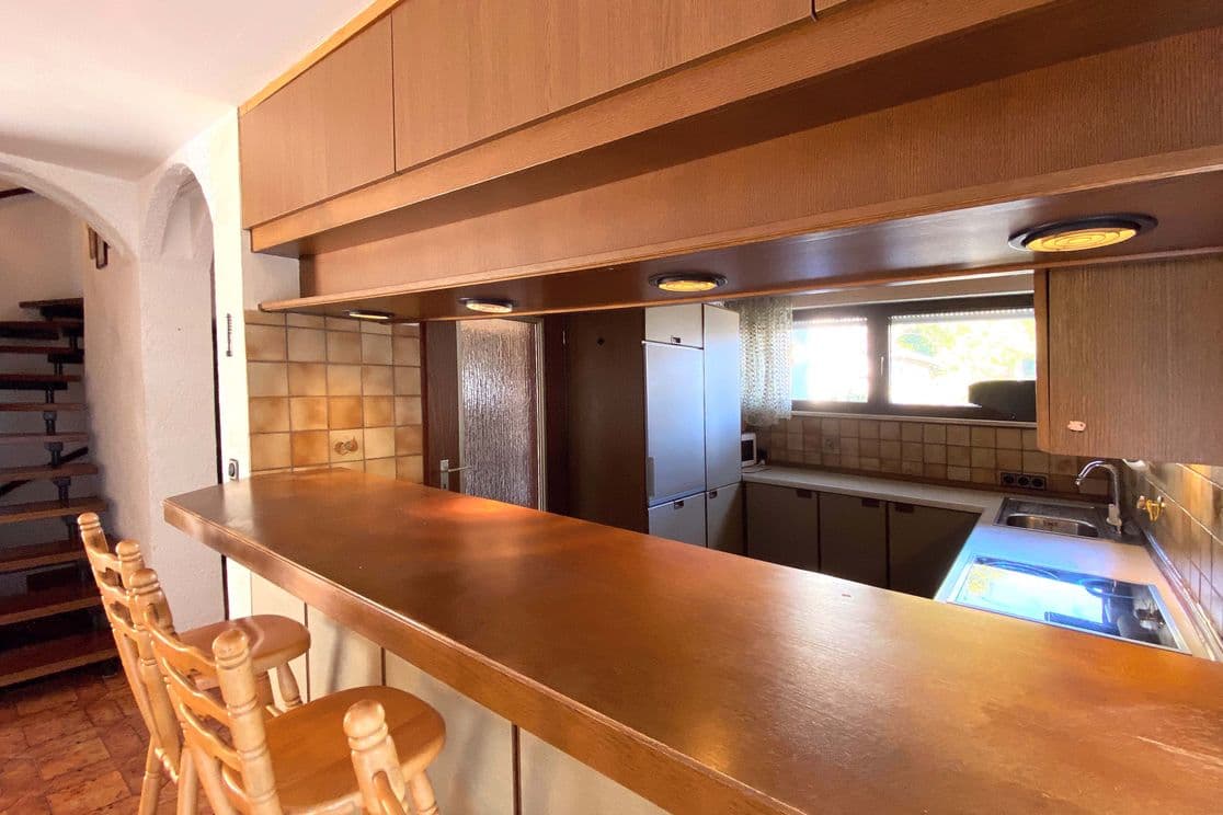 Vintage fitted kitchen with wooden fronts, serving hatch and bar stools in original 1970s design