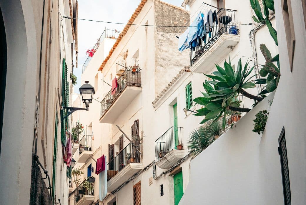 Charmante Straßenszene in Ibizas Altstadt mit traditionellen weiß getünchten Natursteinhäusern, engen Kopfsteinpflastergassen und authentischem mediterranem Flair.