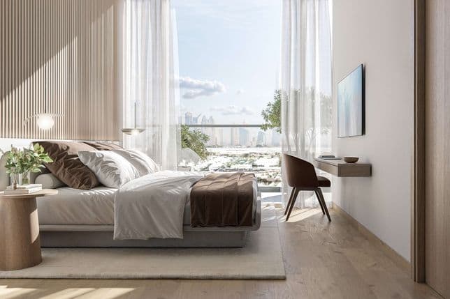 Sunlit master bedroom in Taiyo Residences featuring soft neutral tones, a minimalist desk setup, and floor-to-ceiling glass doors opening to a balcony with skyline views.