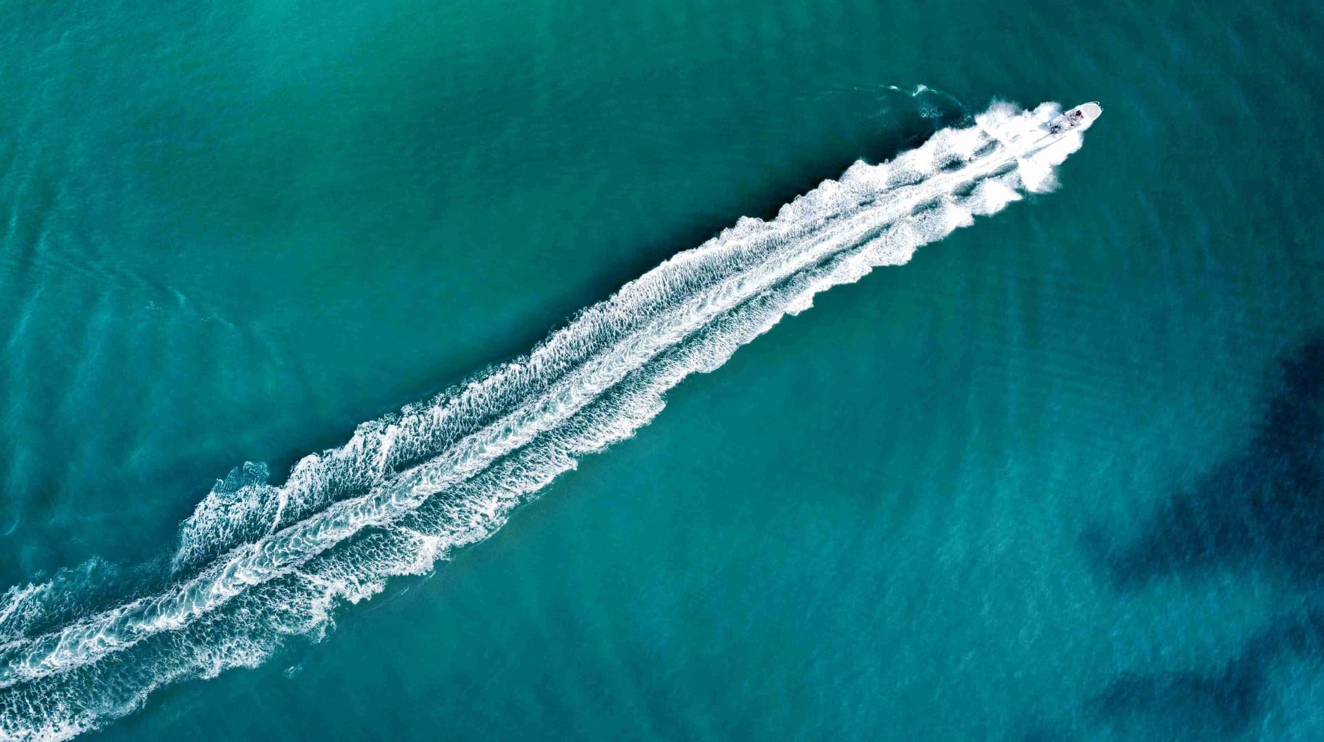 Vista aèria d'una barca navegant per les aigües cristal·lines del mar Mediterrani.