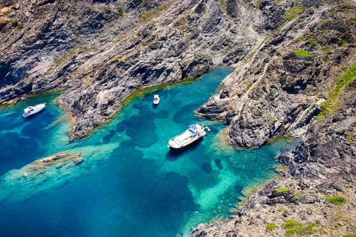 Mar azul turquesa con una costa escarpada y tres barcos en las calas de Empuriabrava