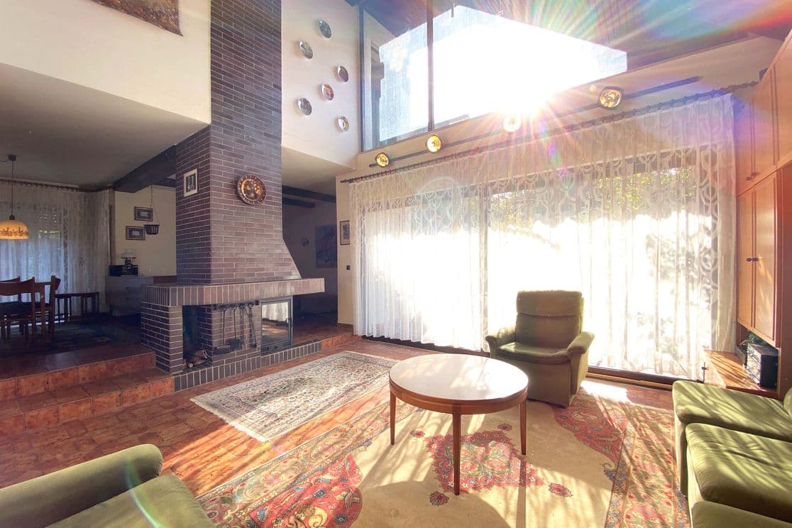 Living room with brick fireplace, high windows, carpet flooring, and 1970s furnishings before renovation