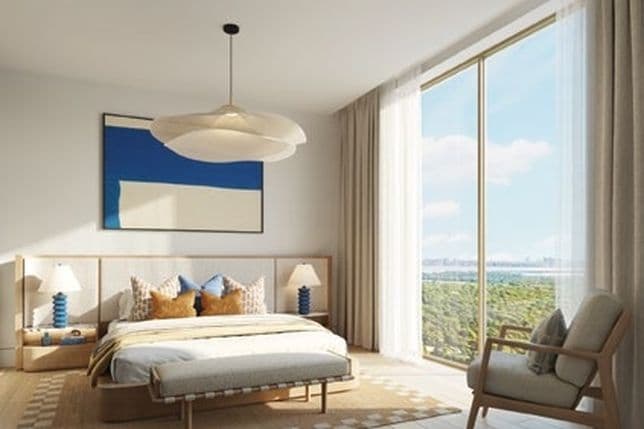 Serene master bedroom with large window, natural wood flooring, contemporary furnishings, and a soft color palette creating a calming beachside atmosphere.
