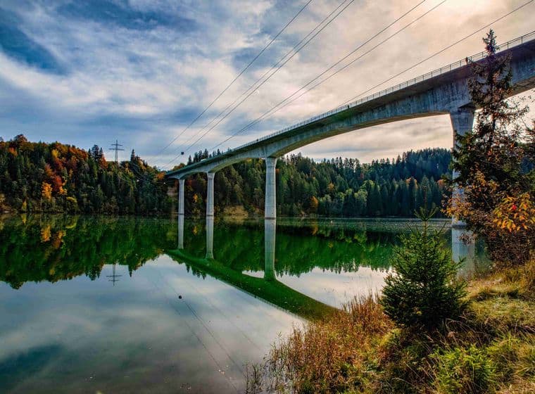 Lechtal Bridge in Schongau, Bavaria – modern concrete structure spanning a lake with forested hills in autumn colors