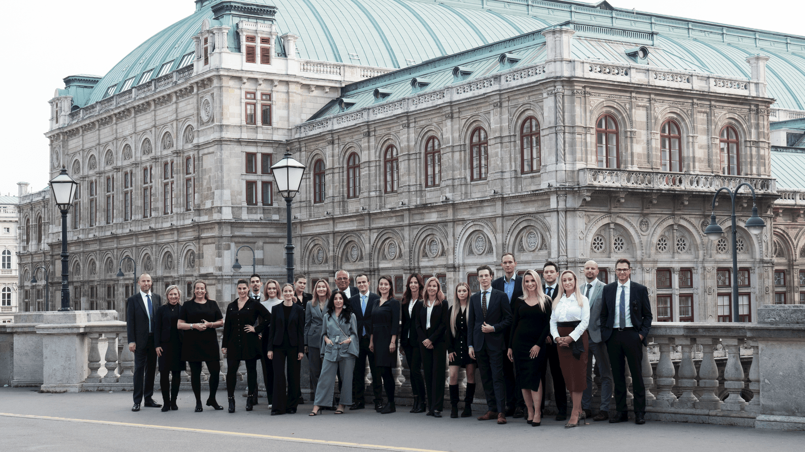 Eine Gruppe von Menschen in formeller Kleidung steht vor der Wiener Oper