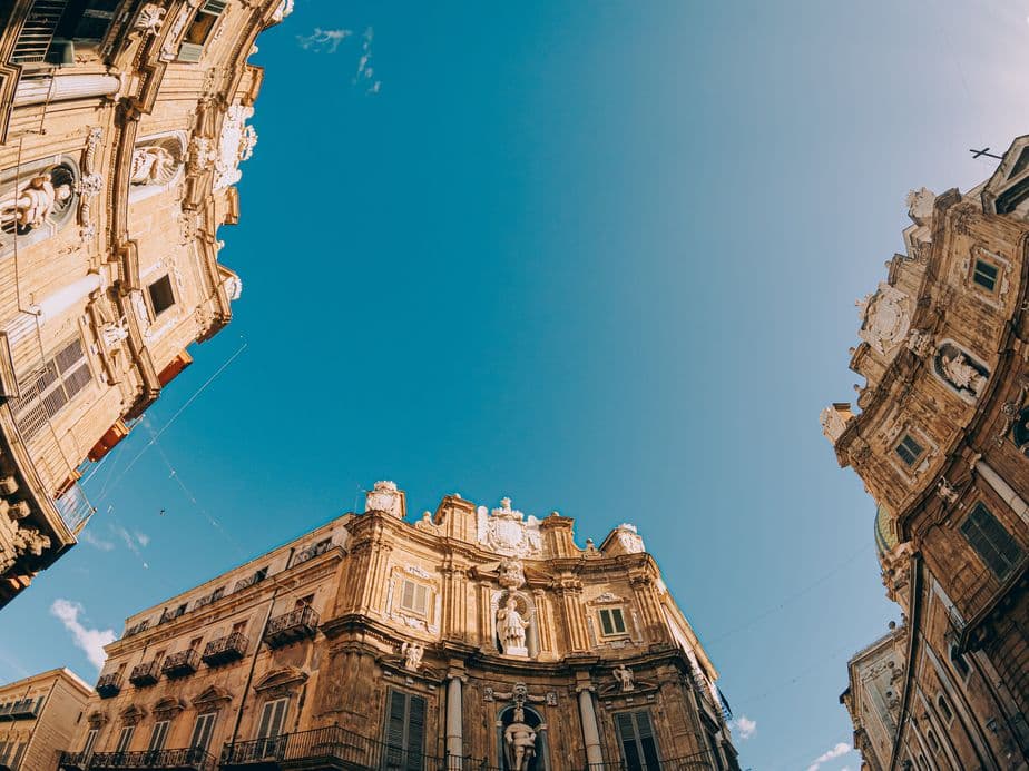 Low-angle view of ornate, historic buildings with sculptures against a clear blue sky.