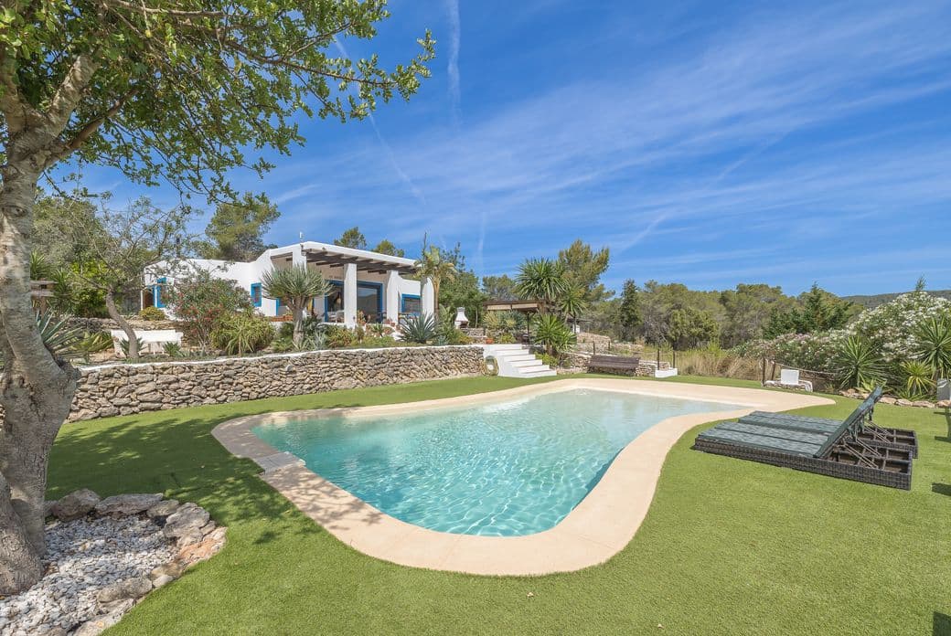 Wunderschöne Villa im typischen Ibiza-Stil, umgeben von einem grünen Garten, mit privatem Pool, weiß getünchten Wänden und authentischem mediterranen Charme – ideal für entspanntes Leben im Freien.