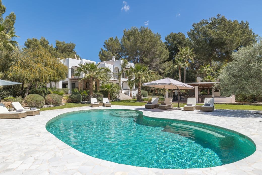 Zeitgenössische Villa Can Verano auf Ibiza mit klarer, weißer Architektur, einem ruhigen Privatpool und üppiger mediterraner Vegetation – für eine frische und entspannte Atmosphäre.