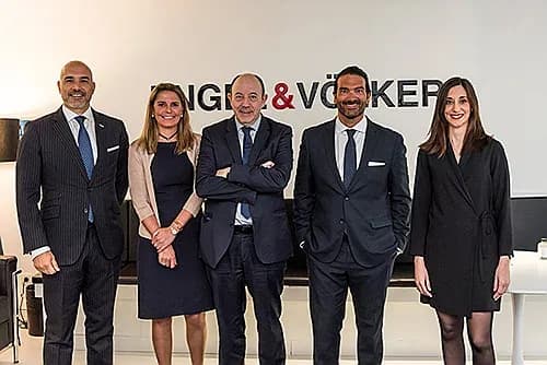 Five real estate agents stand in front of a white wall with the "Engel & Völkers" logo. They are all wearing business attire.