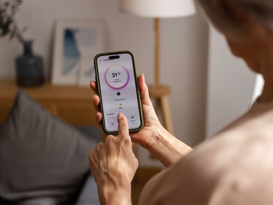 Senior woman adjusting thermostat on smartphone app stock photo