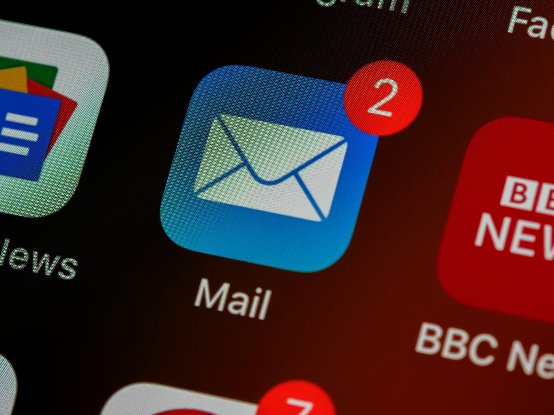 Close-up of a phone screen showing a blue "Mail" app icon with a red notification badge displaying the number "2".