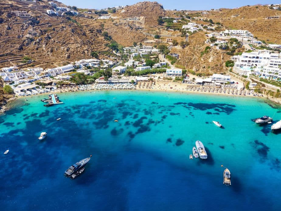 Aerial view of a beach with turquoise water, white buildings, and boats.