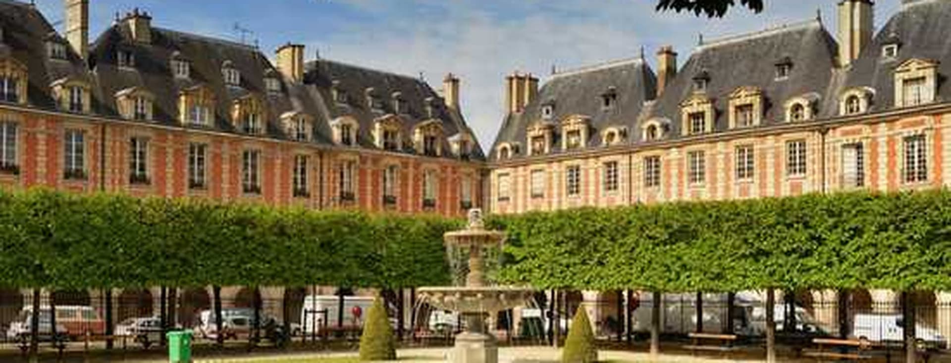 A Parisian square with a fountain, green lawn, and trimmed trees. Buildings with orange brick and gray roofs surround the square.