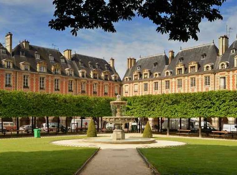 Une place parisienne avec une fontaine, une pelouse verte et des arbres taillés. Des bâtiments en briques orange et aux toits gris entourent la place.