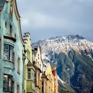 Bunte Altstadthäuser in Innsbruck vor der schneebedeckten Nordkette im Herbstlicht