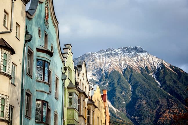 Bunte Altstadthäuser in Innsbruck vor der schneebedeckten Nordkette im Herbstlicht