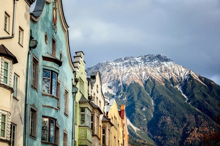 Bunte Altstadthäuser in Innsbruck vor der schneebedeckten Nordkette im Herbstlicht