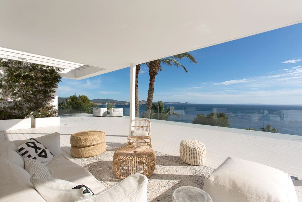 Großzügige obere Terrasse einer exklusiven Ibiza-Villa mit stilvollen Outdoor-Möbeln, natürlichen Materialien und einem atemberaubenden Panoramablick auf das Mittelmeer und die umliegende Küstenlandschaft.