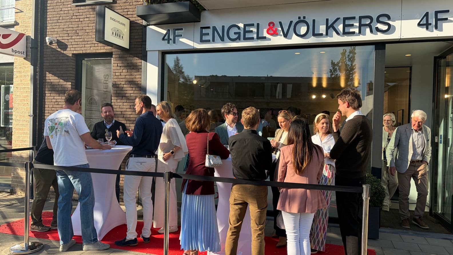 People standing outside a white Engel & Völkers building with large windows and a balloon decoration near the entrance.