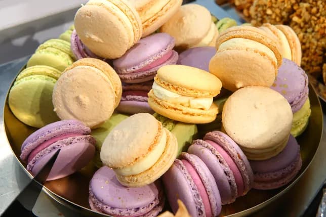 A selection of carefully shaped desserts resembling pears, blueberries and citrus fruits, displayed on golden bases.