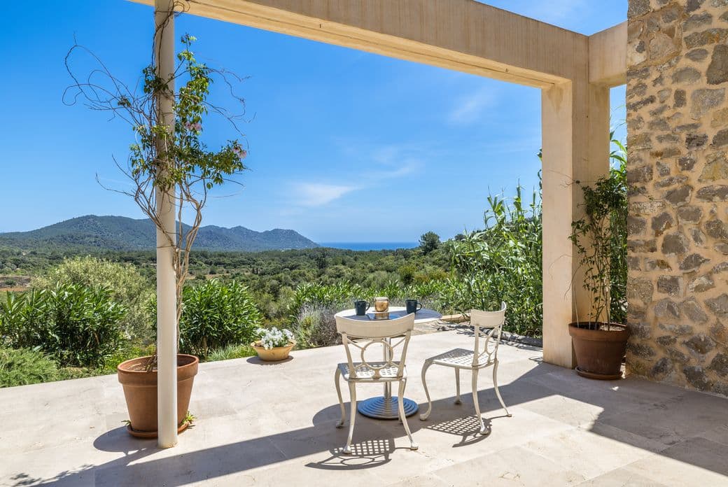 Serena terrassa d'una finca a Son Servera, amb vistes panoràmiques a les muntanyes circumdants i una vista llunyana del mar a l'horitzó.