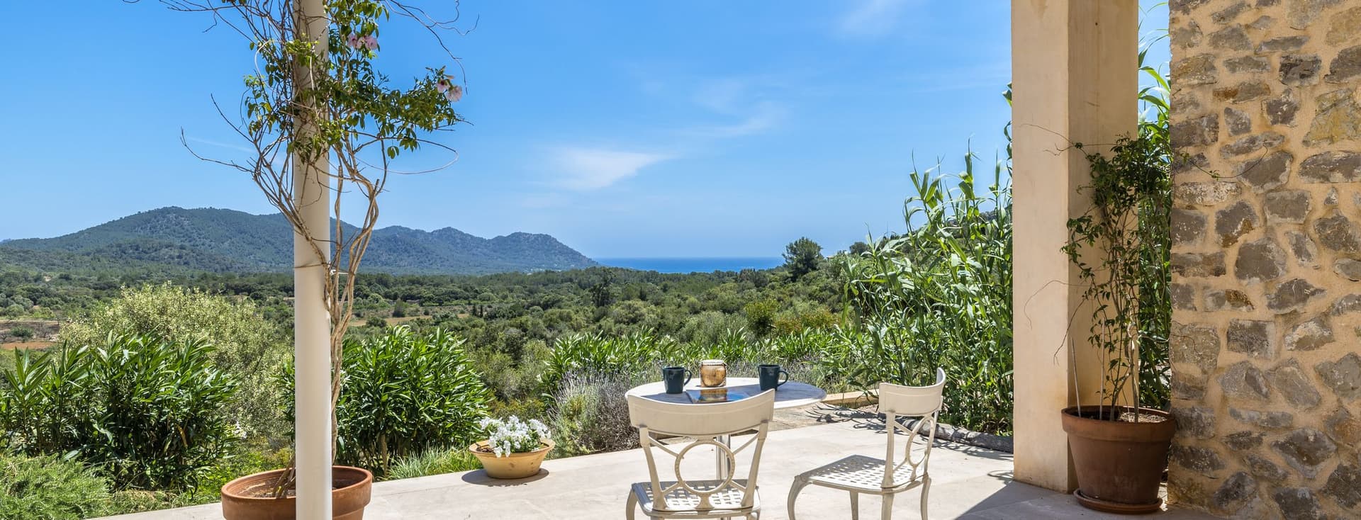 Serena terrassa d’una finca a Son Servera, amb vistes panoràmiques a les muntanyes que l’envolten i una vista llunyana del mar a l’horitzó