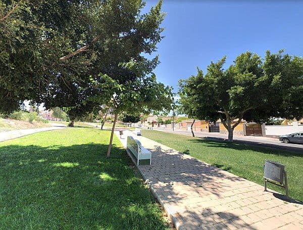 Es veu un parc a Torrevella amb arbres, bancs i un cel blau.