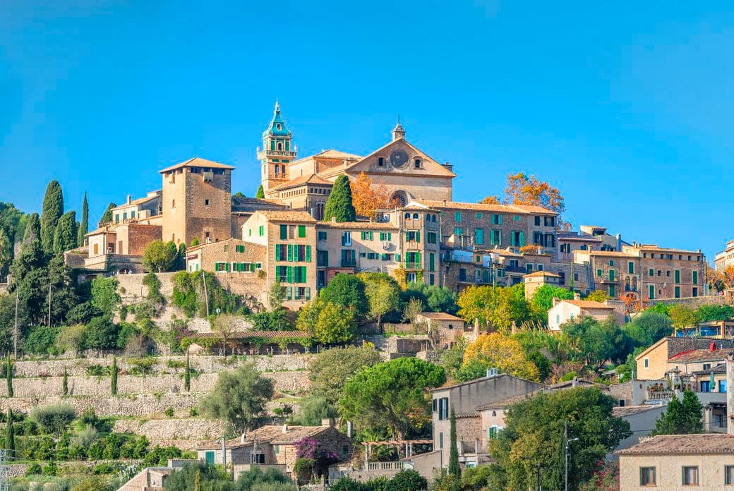 Scenic view of Valldemossa village in Mallorca, highlighting the church as the highest landmark above stone houses and greenery