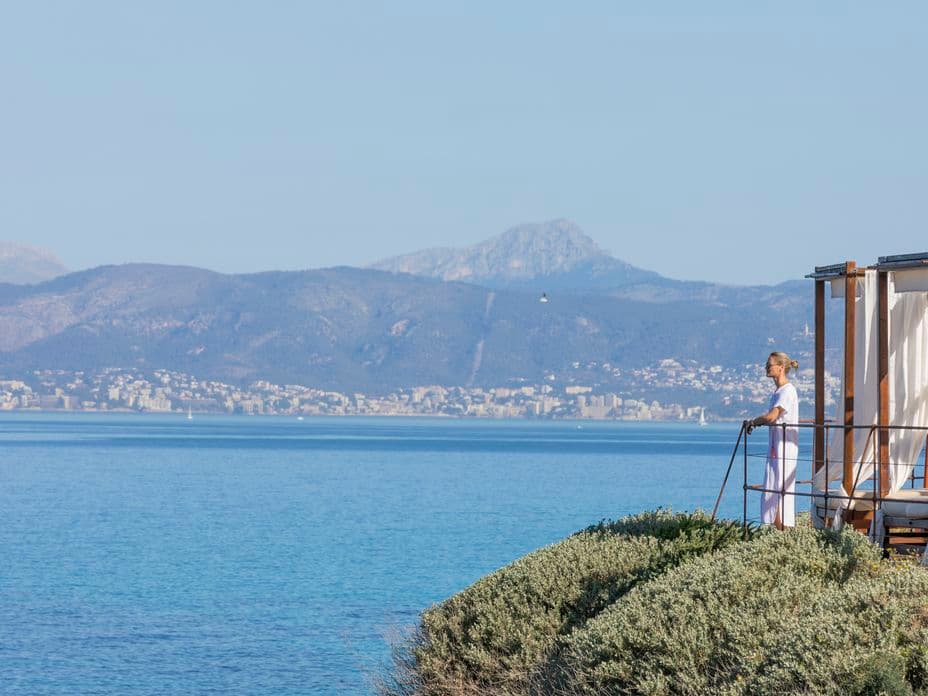 Mujer disfrutando de la vista en Mhares Beach Club, Puig de Ros, con vistas a la bahía de Palma y las montañas al fondo.