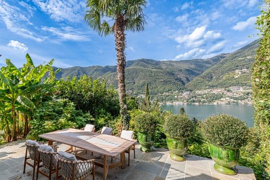 Gedeckter Essbereich unter Palmen mit Panoramablick auf den Comer See