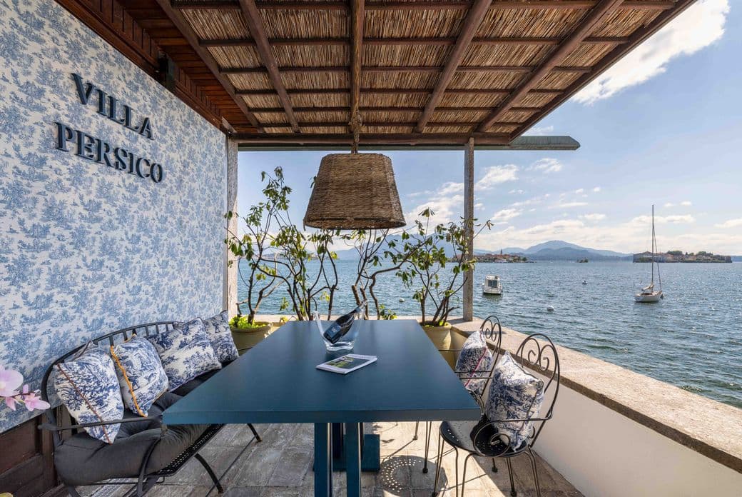 Villa Persico con terrazza spaziosa, tavolo da pranzo all’aperto e vista panoramica sul lago, immersa in un paesaggio naturale.