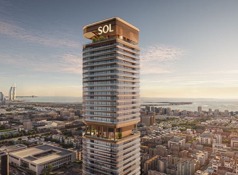Tall modern skyscraper labeled "SOL" with terraces, overlooking a cityscape and ocean, with a famous sail-shaped hotel in the background.