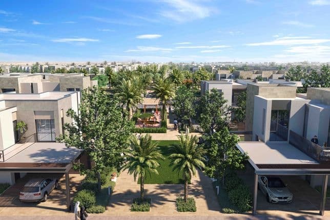 Aerial view of landscaped villas in Arabian Ranches 3 with central green spine featuring palm trees, shaded seating areas, and walking paths connecting the homes.