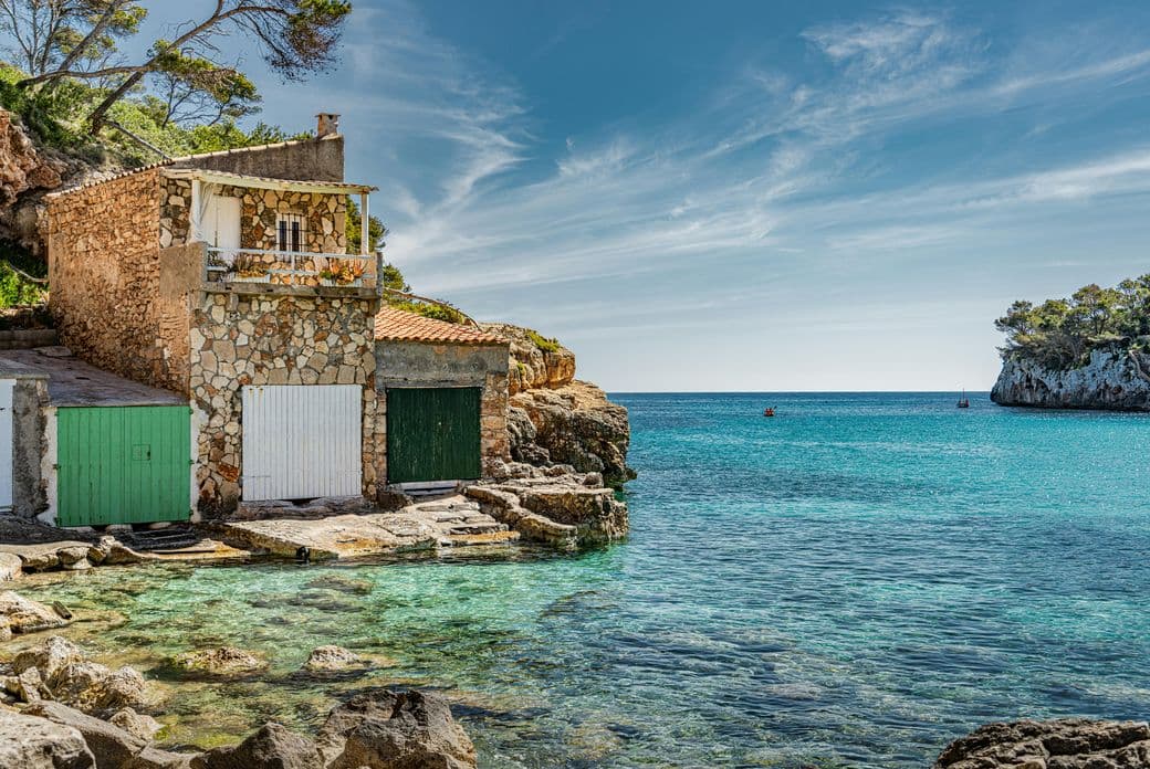 Idyllic beach scene at Cala Llombards, featuring turquoise waters, soft white sand, and dramatic cliffs typical of Mallorca’s southeast coast