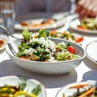 Neun Gerichte der mediterranen Küche, Salate und zwei Personen, die essen.