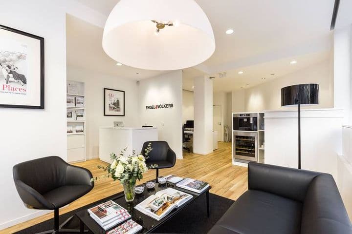 Engel & Völkers office lobby with black leather seating, a black coffee table with magazines, and a white reception desk.
